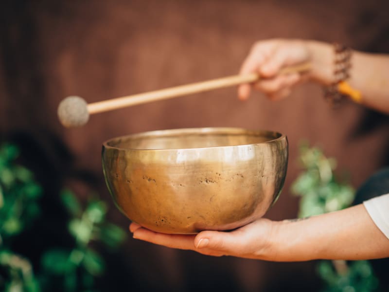 Person striking a singing bowl.