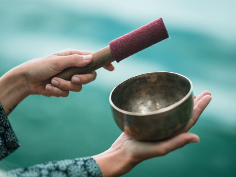 Hands holding singing bowl and mallet.