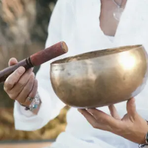 Person holding singing bowl and mallet.