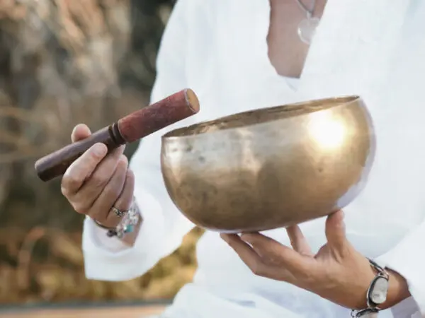 Person holding singing bowl and mallet.