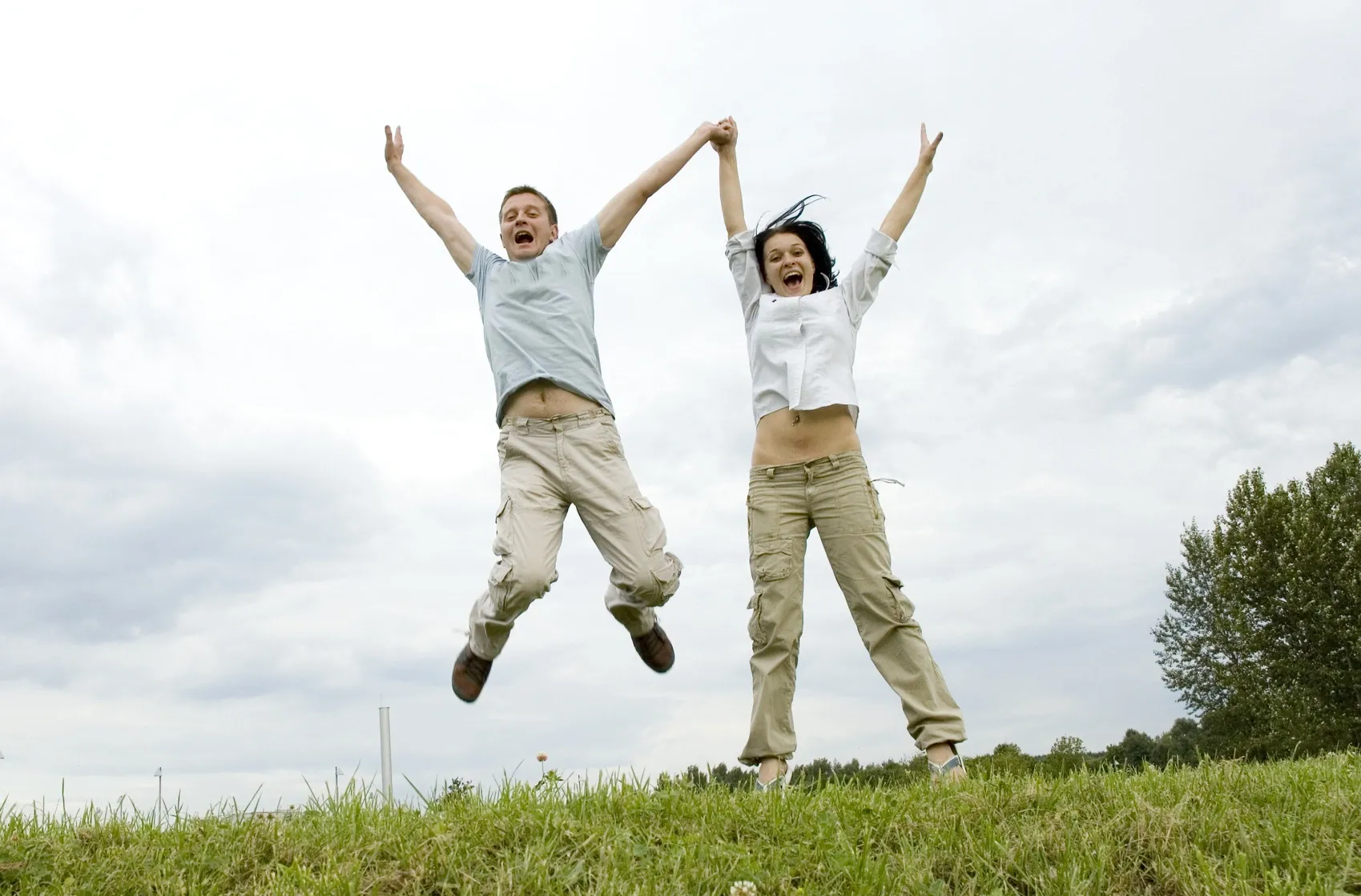 Two people jumping in the air with their hands up.